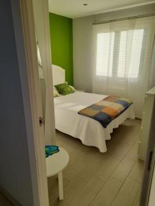 - une chambre avec un lit blanc et un mur vert dans l'établissement La Boquerona, à Polanco