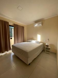 a bedroom with a large bed and a window at Suites O Vencedor in Búzios