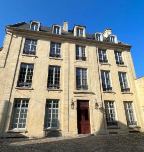 - un grand bâtiment en pierre avec une porte rouge dans l'établissement Appartement de charme, à Bayeux