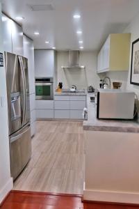 una cocina con electrodomésticos de acero inoxidable y armarios blancos en 1BR Beachfront Condo in Holywood, FL, en Hollywood