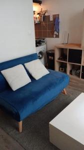 niebieska kanapa z dwoma białymi poduszkami w salonie w obiekcie Appartement en plein coeur du 10eme et proche de plusieurs Gares w Paryżu