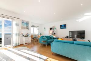 ein Wohnzimmer mit blauen Sofas und einem TV in der Unterkunft Vibing & Liming Ericeira in Ericeira