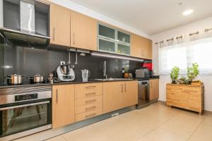 una cocina con armarios de madera y electrodomésticos de acero inoxidable en Vibing & Liming Ericeira, en Ericeira