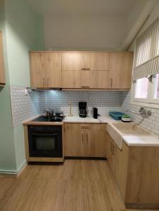雅典的住宿－Apartment Thisio，厨房配有木制橱柜、水槽和炉灶。