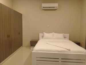 um quarto com uma cama branca e ar condicionado em Star Dubai Apartment em Salalah