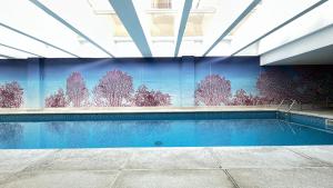 a swimming pool with a mural of trees on the wall at Studio Batel com ótima localização in Curitiba