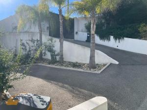 a parking lot with two palm trees next to a wall at COTTAGE MARIN avec VUE MER in Nice