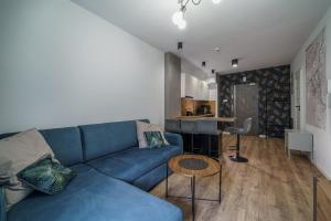uma sala de estar com um sofá azul e uma cozinha em Apartament16 Źródlana MountainAparts em Świeradów-Zdrój