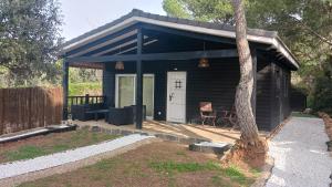 eine kleine Hütte mit einer Veranda und einem Baum in der Unterkunft La cabaña de Uceda in Uceda