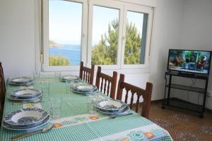 een eetkamer met een tafel met stoelen en een televisie bij Casa en primera linea de mar. in Laxe