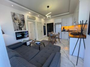 uma sala de estar com um sofá azul e uma cozinha em Holiday 7 Kestel em Alanya