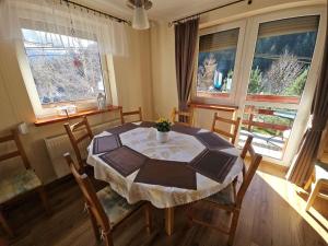 een eetkamer met een tafel, stoelen en ramen bij Zawoja 1895 sauna bania in Zawoja