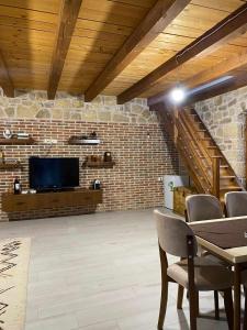 a living room with a tv and a brick wall at Bujtina Salko in Muçaj