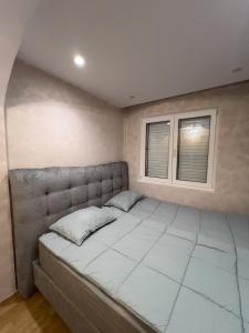 een groot bed in een kamer met 2 ramen bij City Gem: Stylish Urban Hideout in Budva