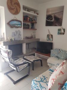 sala de estar con TV, silla y sofá en Casa Lupo, en Stintino