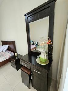 - une commode noire avec un miroir et une lampe dans l'établissement ZLEEP, à Ajman