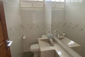 a white bathroom with a toilet and a sink at Ampla casa com piscina na Pituba in Salvador