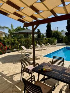 a table with chairs and an umbrella next to a pool at Villa Lorena Protaras in Protaras