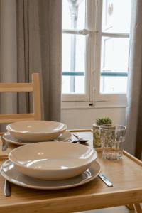 a wooden table with two white plates and a window at Cosy studio centre Versailles in Versailles