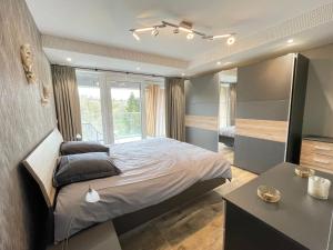 a bedroom with a large bed and a window at Penthouse au lac de Warfaaz in Spa