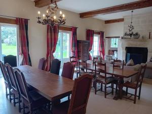 a dining room with a wooden table and chairs at Magnifique château rénové proche bourg grand parc belle terrasse billard, ping pong, proche Bayeux et plages du débarquement in Tilly-sur-Seulles