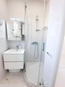 a white bathroom with a shower and a sink at Apartments Alfa in Baška