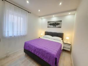 a bedroom with a purple bed and a window at Apartments Alfa in Baška