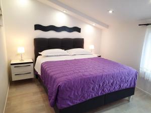 a bedroom with a bed with a purple bedspread at Apartments Alfa in Baška