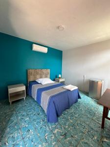 1 dormitorio con cama y pared azul en The FLORENTHINA'S House en Oaxaca de Juárez
