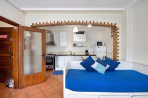 a bedroom with a blue bed and a kitchen at Manny's place - by the sea in Gafanha da Nazaré