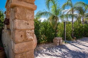 a brick wall with trees and palm trees in the background at Villa del Papiro Charme Apartments in Avola