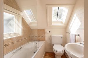 a bathroom with a toilet and a tub and a sink at The Sail Loft (part of Manor House) in Port Isaac