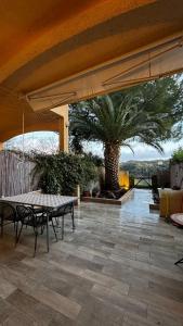 a patio with a table and a palm tree at Casetta Valle Verde in Capalbio