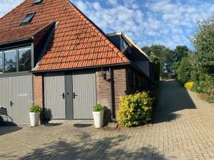 a brick house with an orange roof and a driveway at B&B Buurvrouw Buurman in Blankenham
