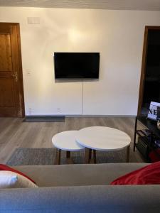 ein Wohnzimmer mit 2 Tischen und einem Flachbild-TV in der Unterkunft Au numéro 12 