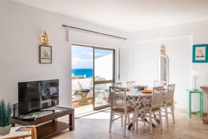a living room with a table and chairs and a television at Casa Cerro Branco in Albufeira