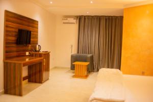 a living room with a desk and a television at Jimaco Hotels and Suites in Uyo