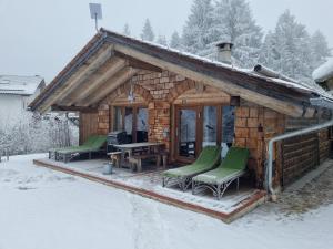 a log cabin with green chairs in the snow at Casa Royal - Schönes Blockhaus mit Außensauna und Bade-Bottich in Sankt Englmar