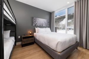 Un dormitorio con una gran cama blanca y una ventana en Les Appartements du Massif de Charlevoix en Petite-Rivière-Saint-François