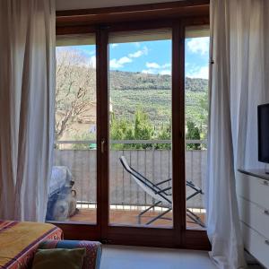 een kamer met een glazen schuifdeur met een stoel op een balkon bij CASA degli OLIVI GARDA LAKE in Riva del Garda