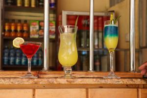 três cocktails sentados num bar em BUNGOMA ROYAL SUITES em Bungoma