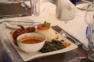 um prato de comida com uma tigela de sopa e arroz em BUNGOMA ROYAL SUITES em Bungoma