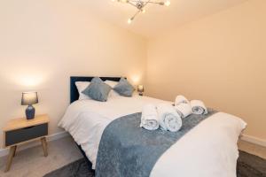 a bedroom with two beds and a night stand with towels at 2 Bedroom Flat Free Parking in Reading