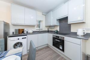 a kitchen with white cabinets and a dishwasher at 2 Bedroom Flat Free Parking in Reading