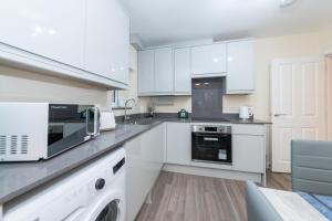a kitchen with white cabinets and a washer and dryer at 2 Bedroom Flat Free Parking in Reading +4 photos