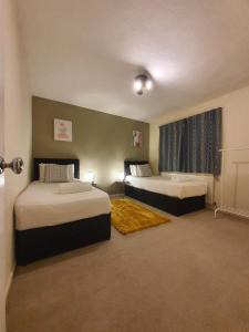 a hotel room with two beds and a bathroom at BridgeCity Spacious Cottage in the Heart of Basingstoke in Worting