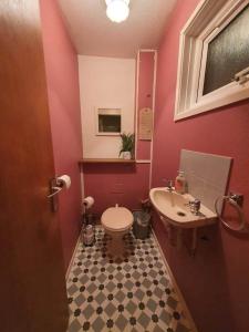 a pink bathroom with a toilet and a sink at BridgeCity Spacious Cottage in the Heart of Basingstoke in Worting