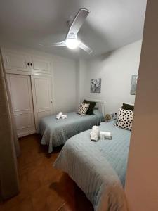 1 dormitorio con 2 camas y ventilador de techo en Apartamento Aniux Chipiona, en Chipiona