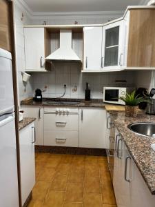 een keuken met witte kasten en een wastafel bij Apartamento el Ermitaño in Chipiona
