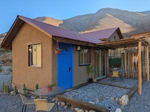 ein kleines Haus mit einer blauen Tür und einem Tisch in der Unterkunft Cumbres de Alcohuaz in Alcoguaz